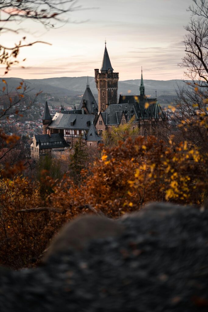 pexels photo 1624735 1624735 A scenic view of Wernigerode Castle surrounded by autumn foliage at sunset.